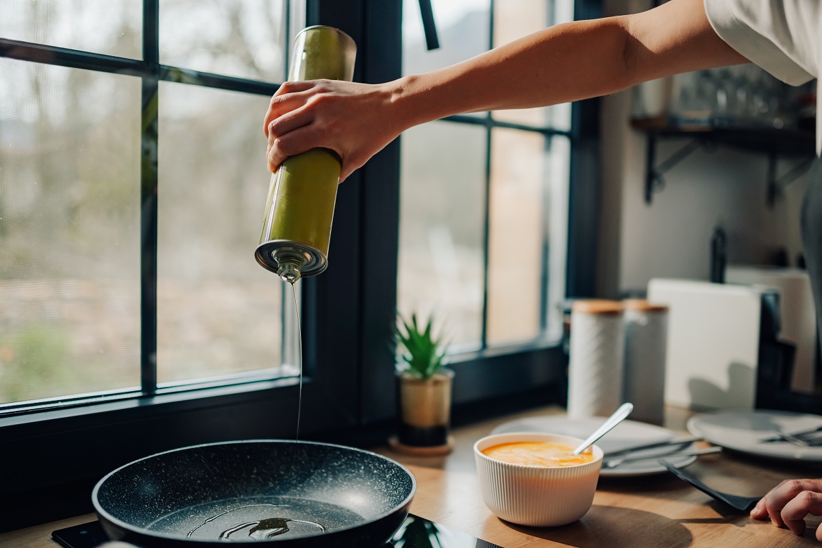 Cooking with Less Oil Just Got Easier with These 13 Tricks chef pouring olive oil into frying pan in kitchen 2024 12 13 18 00 26 utc